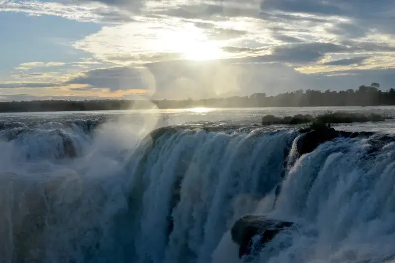 La luz del sol ilumina las Cataratas del Iguazú entre la bruma